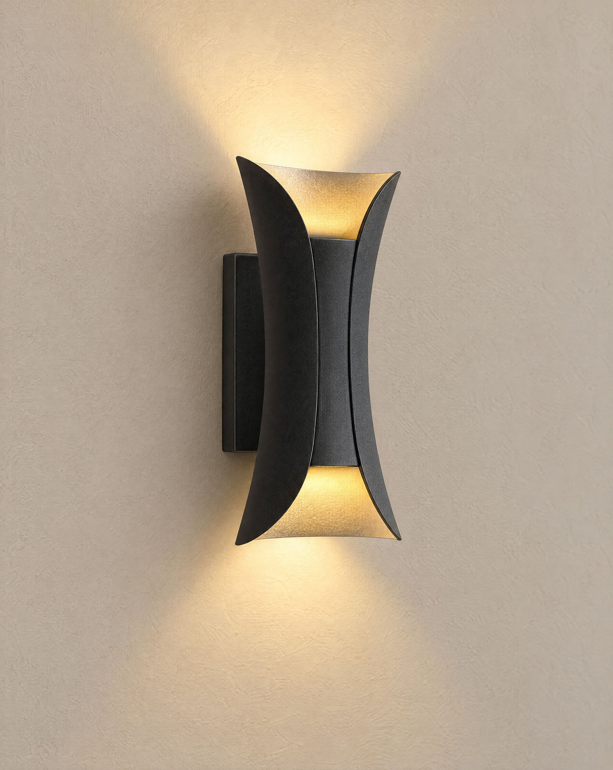 Solsence Vega black and gold up-down LED outdoor wall light lit with warm 3000K glow on a greige wall