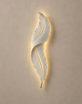 SCI Lighting Plume white feather wall light lit with warm 3000K glow on a greige wall