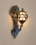 SCI Lighting Pavo colorful peacock wall sconce lit with warm 3000K glow on a greige wall
