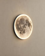 SCI Lighting Orbis moon wall light lit with warm 3000K glow on a greige wall