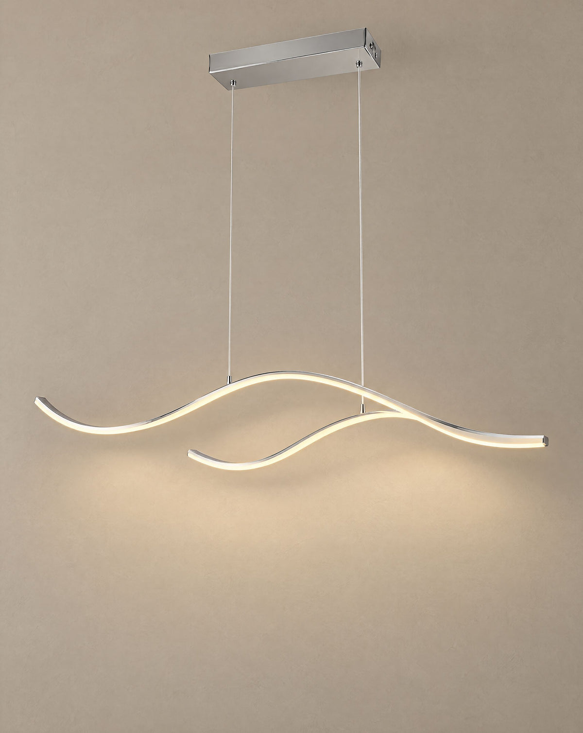 Solsence Crescent chrome wave LED pendant light lit with warm 3000K glow in front of a greige wall