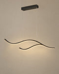 Solsence Crescent black wave LED pendant light lit with warm 3000K glow in front of a greige wall