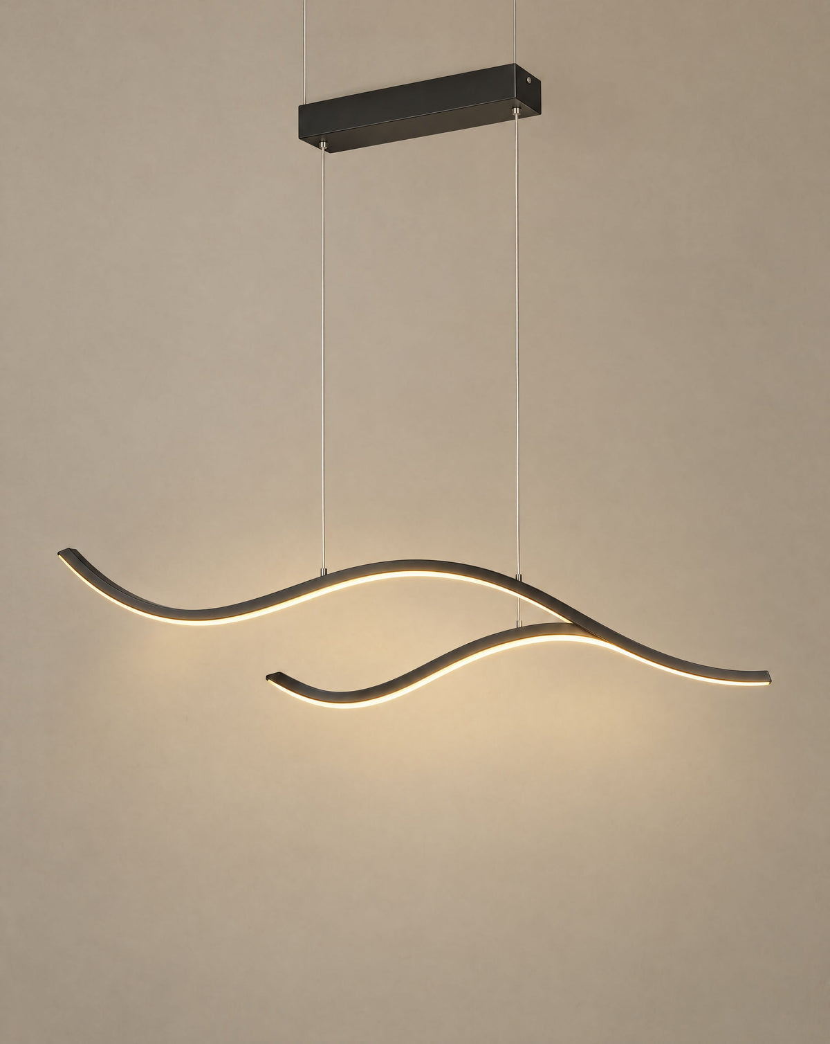 Solsence Crescent black wave LED pendant light lit with warm 3000K glow in front of a greige wall