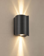 SCI Lighting Onda black up-down LED outdoor wall light lit with warm 3000K glow on a greige wall