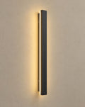 SCI Lighting Linea slim black LED linear outdoor wall light lit with warm 3000K glow on a greige wall