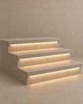 SCI Lighting Stairline under-tread LED strip light lit with warm 3000K glow against a greige backdrop