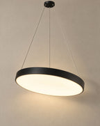 Solsence Halo black round LED ring pendant light lit with warm 3000K glow in front of a greige wall