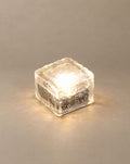 SCI Lighting Glacier solar ice cube step light with warm white glow on a greige backdrop