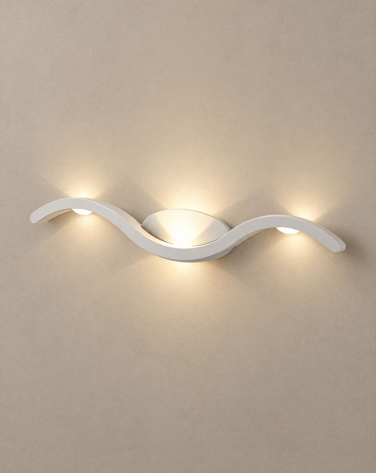 Solsence Tidal white wave wall sconce lit with warm 3000K glow on a greige wall